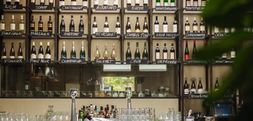 A photograph of a restaurant bar with wine storage on the wall and dozens of bottles.