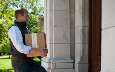 A Domaine employee carries a box of wine into someone's home.