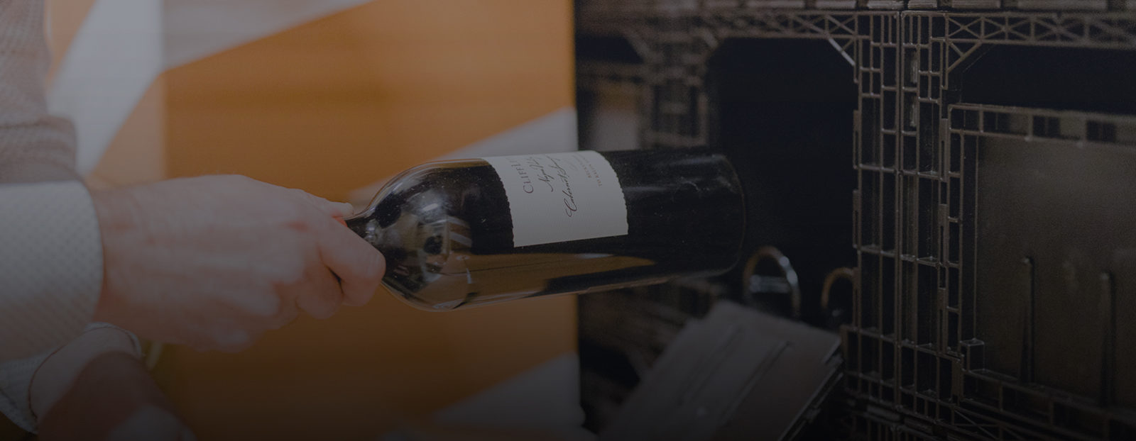 A collector is frequently buying wine and placing one of his new bottles into a Domaine Weinbox for storage.