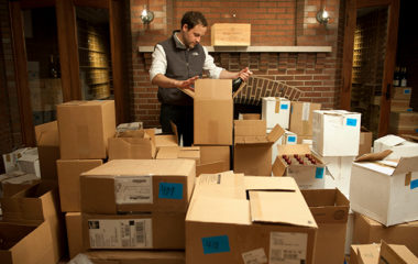 A Domaine employee unpacking boxes of wine in a home as a form of emergency wine cellar management.