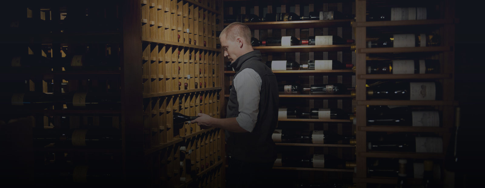 A Domaine employee puts away a bottle of wine as he offers wine cellar management to a client.